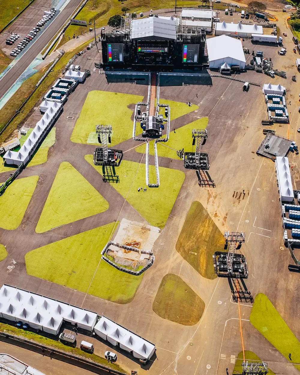 Vista aérea del montaje y la logística de un evento masivo: escenario principal, torres de audio, carpas y áreas de servicio